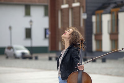 Beautiful woman with violin standing on street