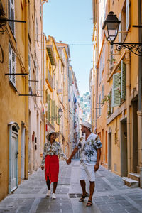 Rear view of people walking on street amidst buildings