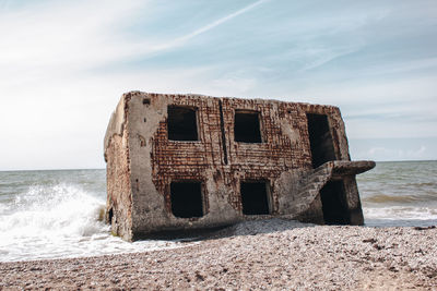 Abandoned built structure on beach against sky