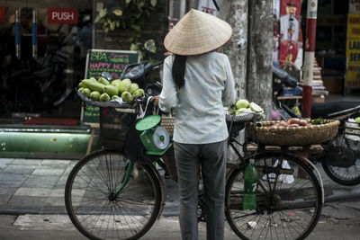 Rear view of woman selling fruits on bicycle