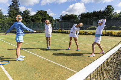 Mature women doing stretching exercises before playing tennis