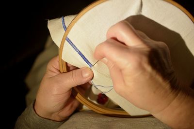 Cropped hands of woman doing embroidery on textile