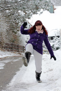 Full length portrait of young woman standing on snow field