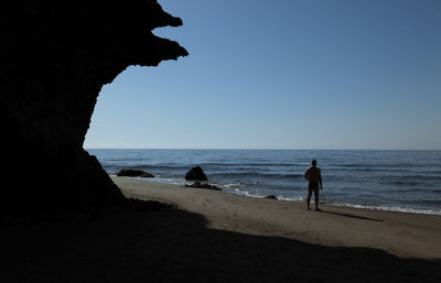 Silhouette people at beach against clear sky