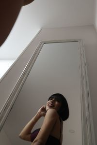Low angle view of smiling woman reflecting on mirror