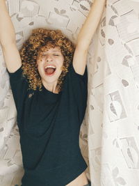 Smiling young woman yawning under blanket