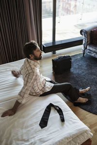 High angle view of businessman relaxing on bed in hotel room