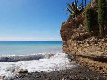 Scenic view of rocks on beach against sky