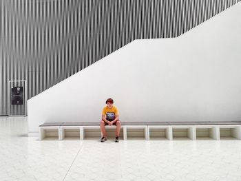 Full length of teenage boy on seat at szczecin philharmonic