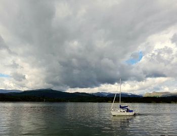 Boats in sea against cloudy sky