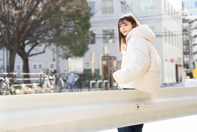 Portrait of young woman standing in city