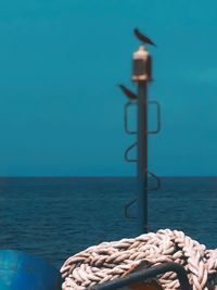 Stack of stones by sea against blue sky