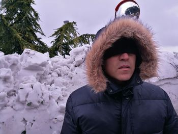 Man wearing winter coat standing against snow