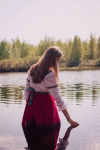 Woman standing in lake against sky