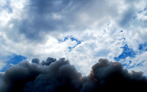 Low angle view of sunlight streaming through clouds