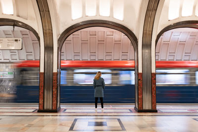 Woman in a blue coat at the metro station. departing train. motion blur 