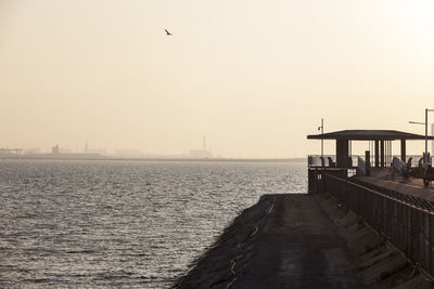 Scenic view of sea by pier against sky