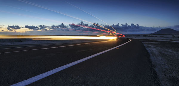 Light trails on road against sky