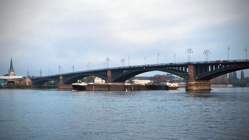 Bridge over river against sky in city