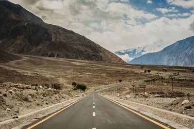 Scenic view of road by mountains against sky