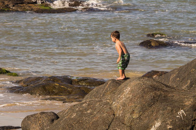 Full length of boy on rock at beach