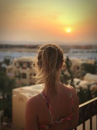 Rear view of woman in city during sunset