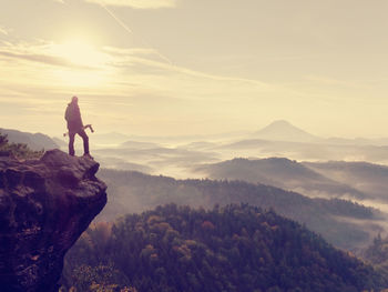 Man standing on rock against sky