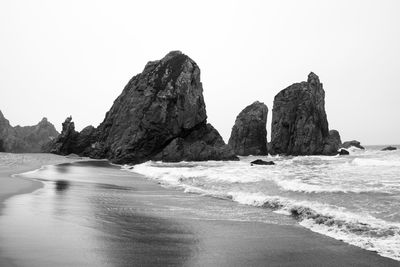 Rocks on beach against clear sky