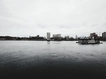 City buildings by sea against sky