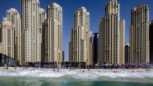Modern buildings by sea against sky