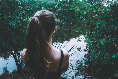 Rear view of woman sitting against trees