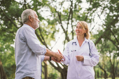 Senior man handshaking with happy doctor in park