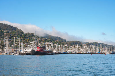 Boats in sea against clear blue sky