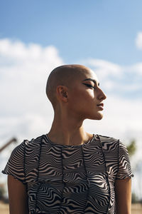 Woman with shaved head in front of sky
