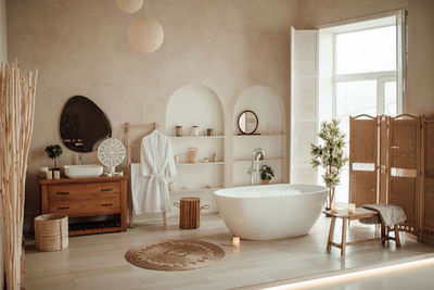 Luxury interior of big bathroom at modern african style with oval bathtub in natural lighting