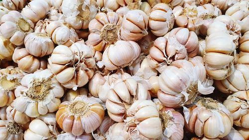 Full frame shot stack of garlics for sale in market
