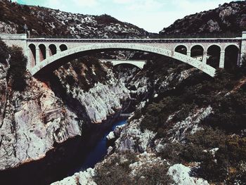 Arch bridge over river against sky