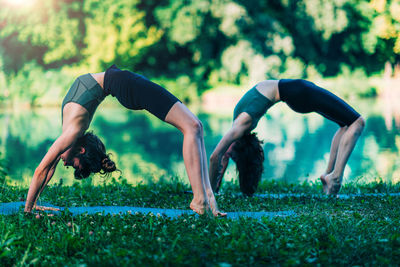 Yoga women by the water. bridge pose.