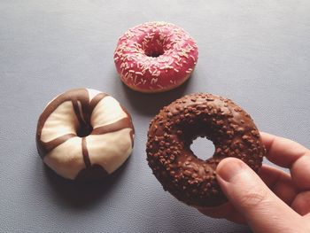 Close-up of cropped hand holding donut on table