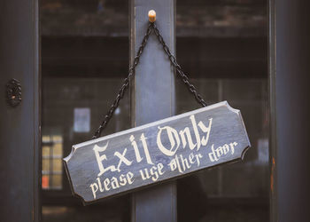 Close-up of exit sign hanging on door