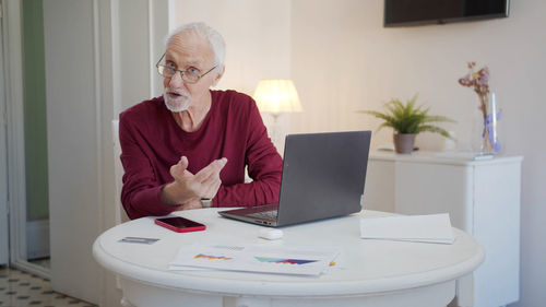 Portrait of senior man using laptop at home