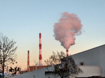 Smoke emitting from factory against clear sky
