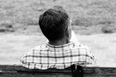 Rear view of man sitting on bench at park