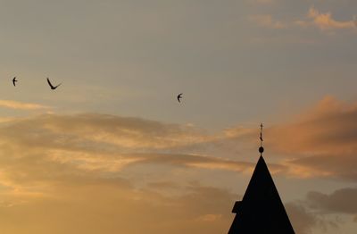 Low angle view of silhouette birds flying against sky during sunset