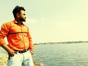 Young man standing in sea against sky