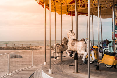 People at amusement park by sea against sky