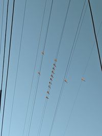 Low angle view of power lines against clear blue sky