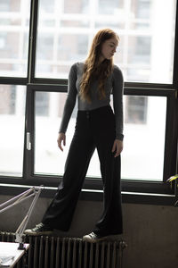 Young woman standing against window