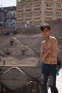 Portrait of young man standing against building in city