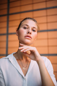Close-up portrait of businesswoman sitting against wall in office